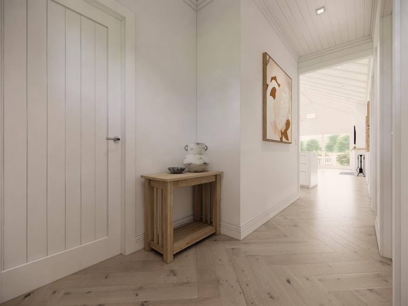 May include: Interior hallway with light wood flooring and white walls. A small wooden table with a decorative vase and bowl sits against the wall. An abstract painting hangs on the wall, and a door is on the left.