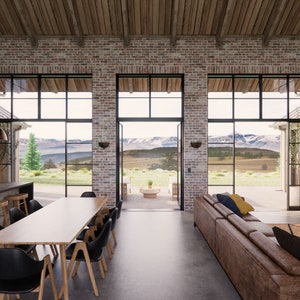View from the entry area of Mill Farm, a house design by Turnervisual. There is an island bench, dining table and lounge that all share a view to mountains in the distance.