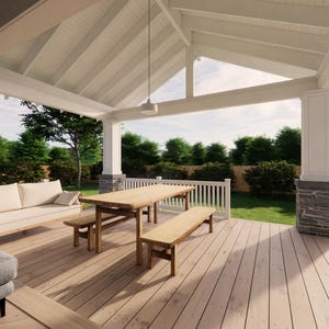 May include: A covered outdoor patio with a wooden deck, a wooden table, and benches. A white sofa with pillows is on the left. The patio has a white ceiling and columns. Green trees and grass are visible in the background.