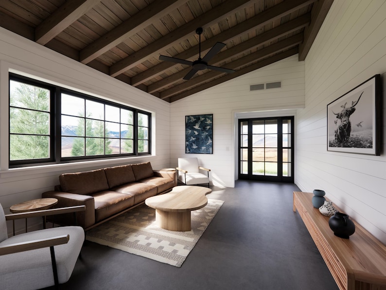 May include: A modern living room with a brown leather sofa, a wooden coffee table, and two white armchairs. The room features large windows with black frames, a black ceiling fan, and a wooden ceiling. Artwork and a rug complete the space.