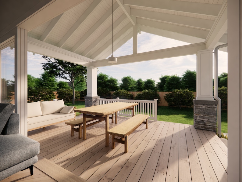 May include: A covered outdoor patio with a wooden deck, a light-colored sofa, and a wooden dining table with benches. The patio has white columns, a white ceiling, and a view of a green lawn and trees.