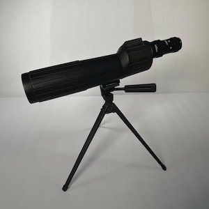 May include: A black spotting scope with a tripod. The scope is cylindrical with a textured grip and a lens at the end. The tripod has three legs and a handle for adjusting the scope's position. The scope is angled upwards.