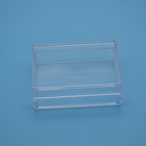 May include: A clear plastic box with a lid. The box is empty and has a rectangular shape.