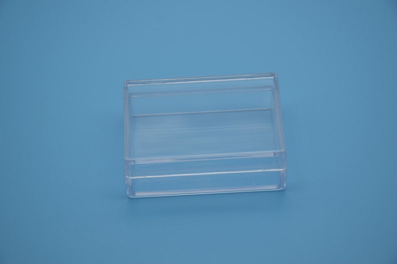 May include: A clear plastic box with a lid. The box is empty and has a rectangular shape.