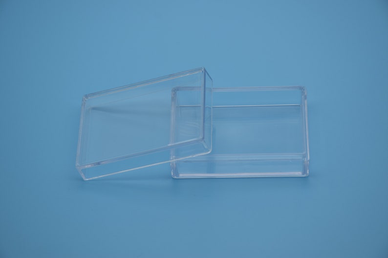 May include: A clear plastic box with a lid. The box is empty and has a rectangular shape.