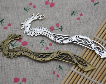 May include: Two silver dragon-shaped bookmarks, one with a bronze finish and the other with a silver finish. Both bookmarks feature intricate details and a Celtic knot design.