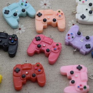 May include: Assortment of colourful plastic game controller charms. The charms are in various colours, including blue, pink, purple, red, yellow, and black. Each charm features a detailed design of a classic game controller.