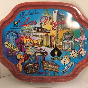 May include: A decorative serving tray with a wooden frame and a colorful Las Vegas themed design. The tray features iconic landmarks, casino signs, and the text "Fabulous Las Vegas".