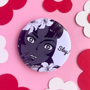 Könnte beinhalten: Ein schwarz-weißer Knopf mit einer Frau mit Blumen im Haar und dem Wort "Slay!" auf dem Knopf.
