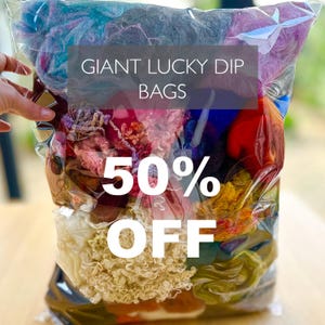 May include: A transparent bag packed with a variety of colourful yarns. The bag includes shades of blue, purple, yellow, and red. Text on the bag reads "GIANT LUCKY DIP BAGS" and "50% OFF".