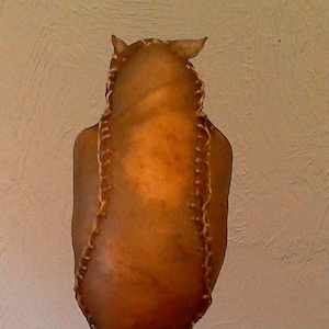 May include: A brown leather owl sculpture with stitched details, mounted on a wooden branch.