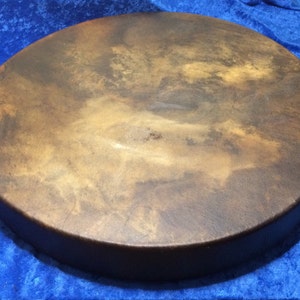 May include: A brown leather drum with a natural finish. The drum is round and has a diameter of approximately 46 cm.