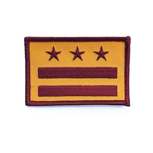 May include: A yellow embroidered patch with three red stars and two red stripes. The patch is surrounded by a red border.
