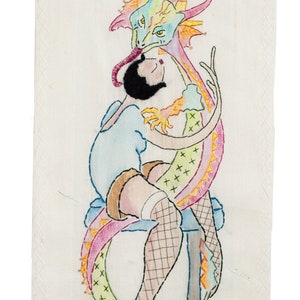May include: A colorful embroidered wall hanging featuring a woman sitting on a stool with a dragon wrapped around her. The dragon is pink, green, and yellow with a blue head. The woman is wearing a blue dress and fishnet stockings.