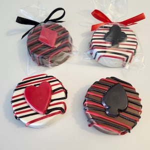 May include: Four chocolate-covered cookies decorated with red and black stripes and playing card symbols. The cookies are individually wrapped in clear cellophane bags with red and black ribbon.