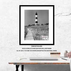 May include: Black and white framed print of a lighthouse with a black and white striped tower, standing tall amidst tall grass. A wooden walkway leads to the lighthouse. The text "Jimmy REA" is visible.