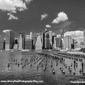 May include: Black and white photograph of the New York City skyline, featuring numerous skyscrapers and buildings along the waterfront. The image includes the text "www.JimmyReaPhotography.Etsy.com" and "Copyright Jimmy Rea".