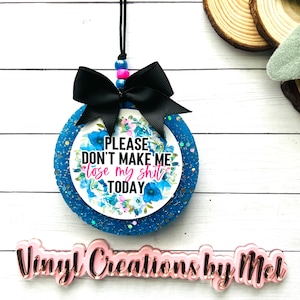 May include: A blue and white glitter car air freshener with a black bow and the text "PLEASE DON'T MAKE ME LOSE MY SHIT TODAY".