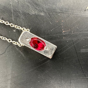 a red stone sitting on top of a metal surface