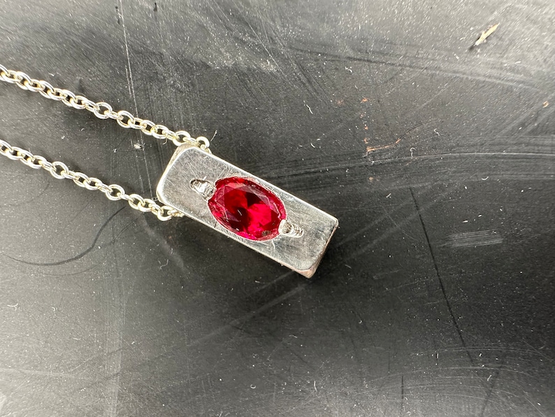 a red stone sitting on top of a metal surface