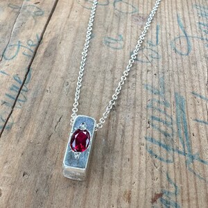a necklace with a red stone in it