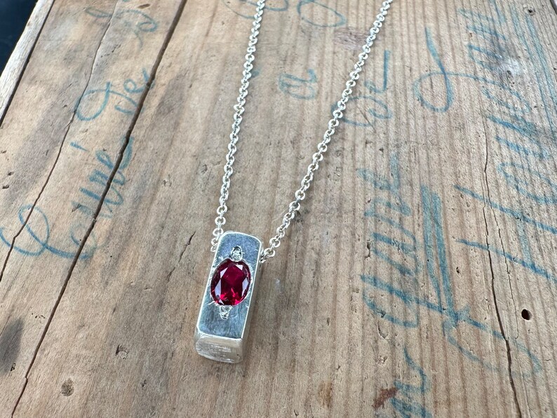 a necklace with a red stone in it