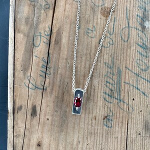a necklace with a red stone hanging from it