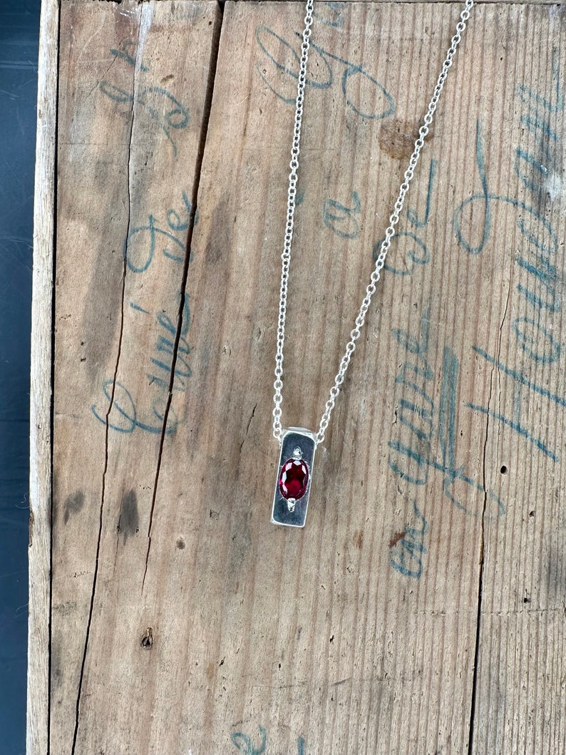 a necklace with a red stone hanging from it