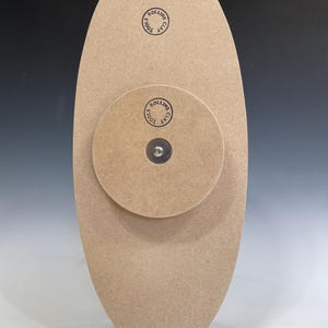 May include: A wooden oval-shaped base with a smaller round wooden base attached to the back. The smaller base has a metal screw in the center. Both bases have the text "CLAY TOOLS ROLLINS" printed on them.