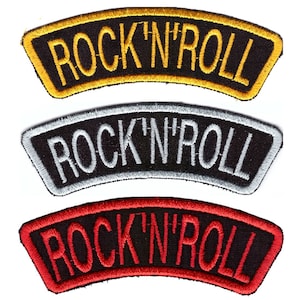 Puede incluir: Tres parches bordados con el texto "ROCK 'N' ROLL". El parche superior tiene un borde y letras doradas, el del medio tiene un borde y letras plateadas, y el inferior tiene un borde y letras rojas. Todos los parches tienen un fondo negro.