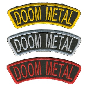 May include: Three embroidered patches with the text "DOOM METAL". The top patch has a yellow border and lettering, the middle one has a silver border and lettering, and the bottom one has a red border and lettering.