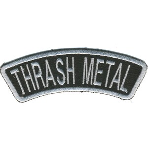 May include: A black, arched patch with the words "THRASH METAL" embroidered in white. The patch has a silver border and is likely designed to be sewn onto clothing or accessories.