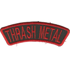May include: A black, arched patch with red embroidered trim and lettering. The text "THRASH METAL" is stitched in red across the center. The patch is likely designed to be sewn onto clothing or accessories.