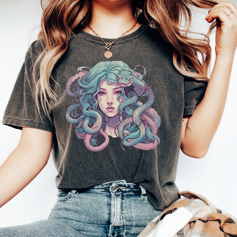 Pode incluir: Uma camiseta cinza escura com uma estampa gr&aacute;fica de uma mulher com cobras azuis e roxas no cabelo.
