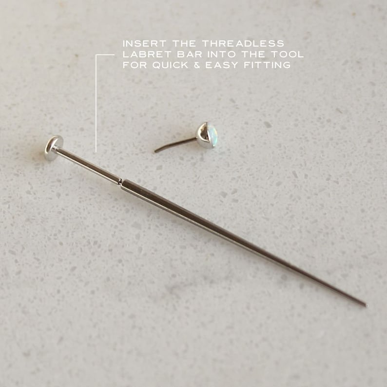 May include: A silver-colored labret bar insertion tool with a small, detached labret stud. The text in the image reads: "INSERT THE THREADLESS LABRET BAR INTO THE TOOL FOR QUICK & EASY FITTING."