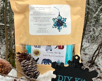 May include: A DIY kit for creating a snowflake holiday ornament. The kit includes all the materials needed to create a beautiful glass mosaic. The kit is labeled "Mosaic Kits By Lola Bug Creations".