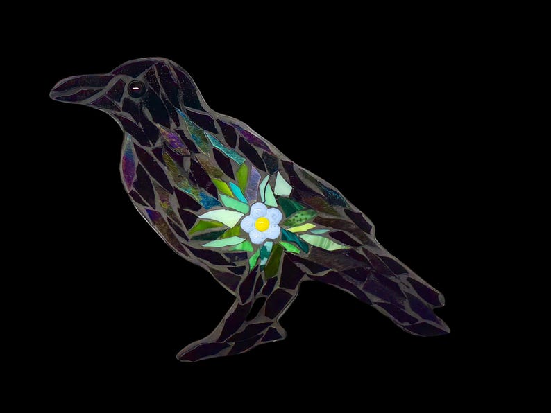 May include: A mosaic glass crow with iridescent purple and black feathers. A white flower with green leaves is embedded in the crow's chest.
