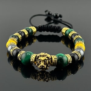 Peut inclure: Un bracelet en perles noires, vertes et jaunes avec un pendentif tête de lion en or. Le bracelet est fait avec un cordon noir et a un nœud coulissant pour ajuster la taille.