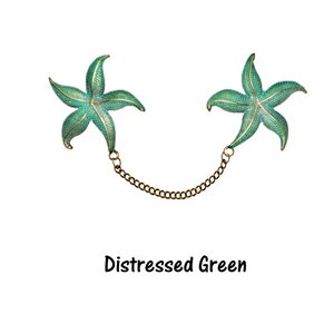 May include: A pair of distressed green starfish brooches connected by a gold chain.