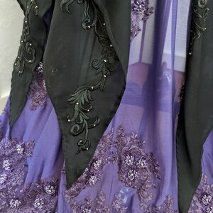 May include: A purple sheer fabric with black lace trim and black embroidered details. The fabric is decorated with small, shiny beads.