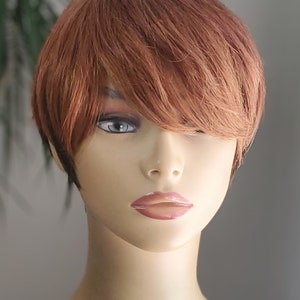Op de afbeelding: Een kort, recht, kastanjebruin pruik met een zijwaarts geveegd pony. De pruik is gestyled op een mannequinhoofd.