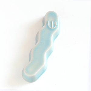 Peut inclure: Une mezuzah en céramique bleu clair avec une lettre hébraïque Shin blanche sur le devant.