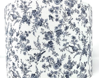 May include: A white lampshade with a blue floral pattern featuring small birds and butterflies.
