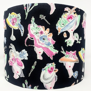 May include: Black fabric lampshade with a repeating pattern of colorful hats and flowers. The hats are in various styles and colors, including pink, blue, and yellow. The flowers are in shades of pink, blue, and green.