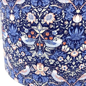 May include: A blue and white fabric with a repeating pattern of stylized birds, flowers, and leaves. The fabric has a vintage aesthetic and is perfect for crafting projects.