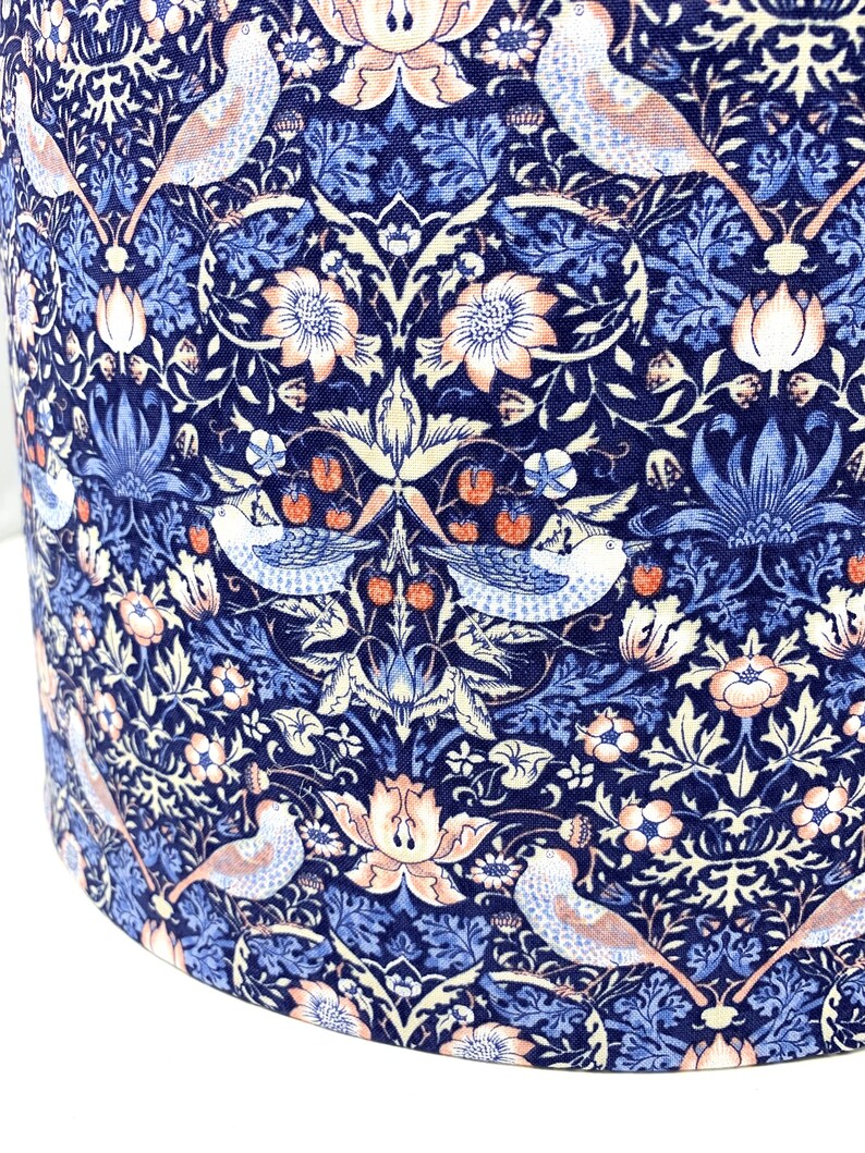 May include: A blue and white fabric with a repeating pattern of stylized birds, flowers, and leaves. The fabric has a vintage aesthetic and is perfect for crafting projects.