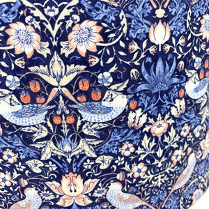 May include: A navy blue fabric with a repeating pattern of stylized birds, flowers, and leaves. The pattern is in shades of blue, pink, and white.