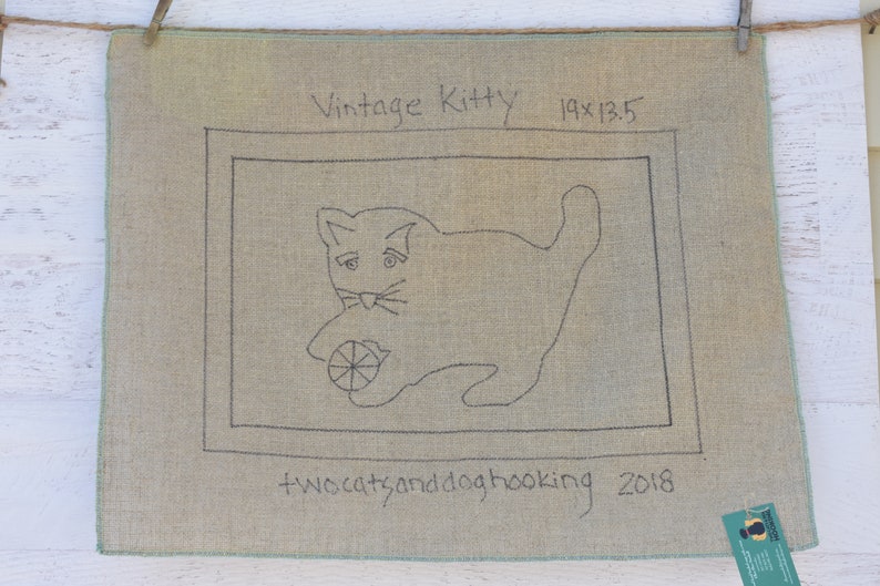 以下が含まれることがあります： ボールで遊ぶ猫の黒い輪郭が描かれたベージュのキャンバス。猫の上に「Vintage Kitty 19x13.5」というテキスト、猫の下に「twocatsanddoghooking 2018」というテキストが書かれている。