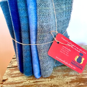 Blue wool collection bundled together with linen thread, a red tag attached and sitting on a chippy stool