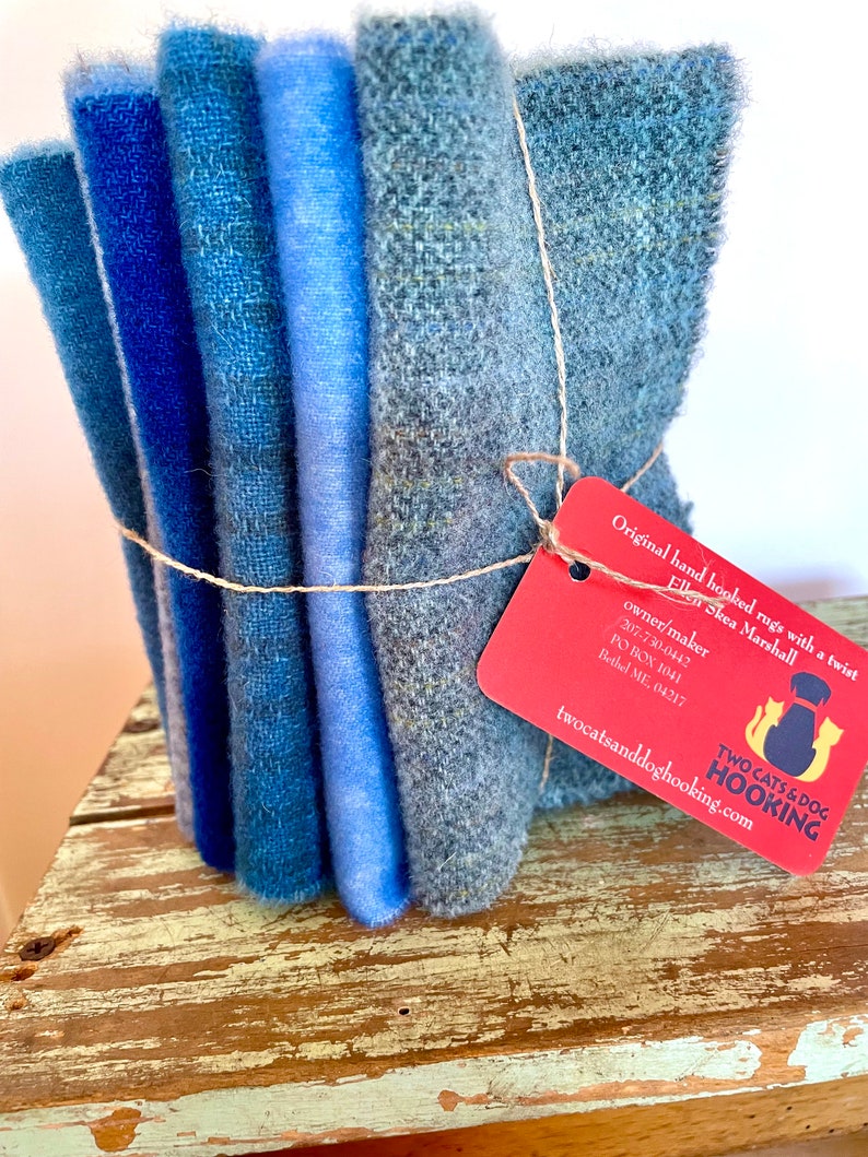 Blue wool collection bundled together with linen thread, a red tag attached and sitting on a chippy stool